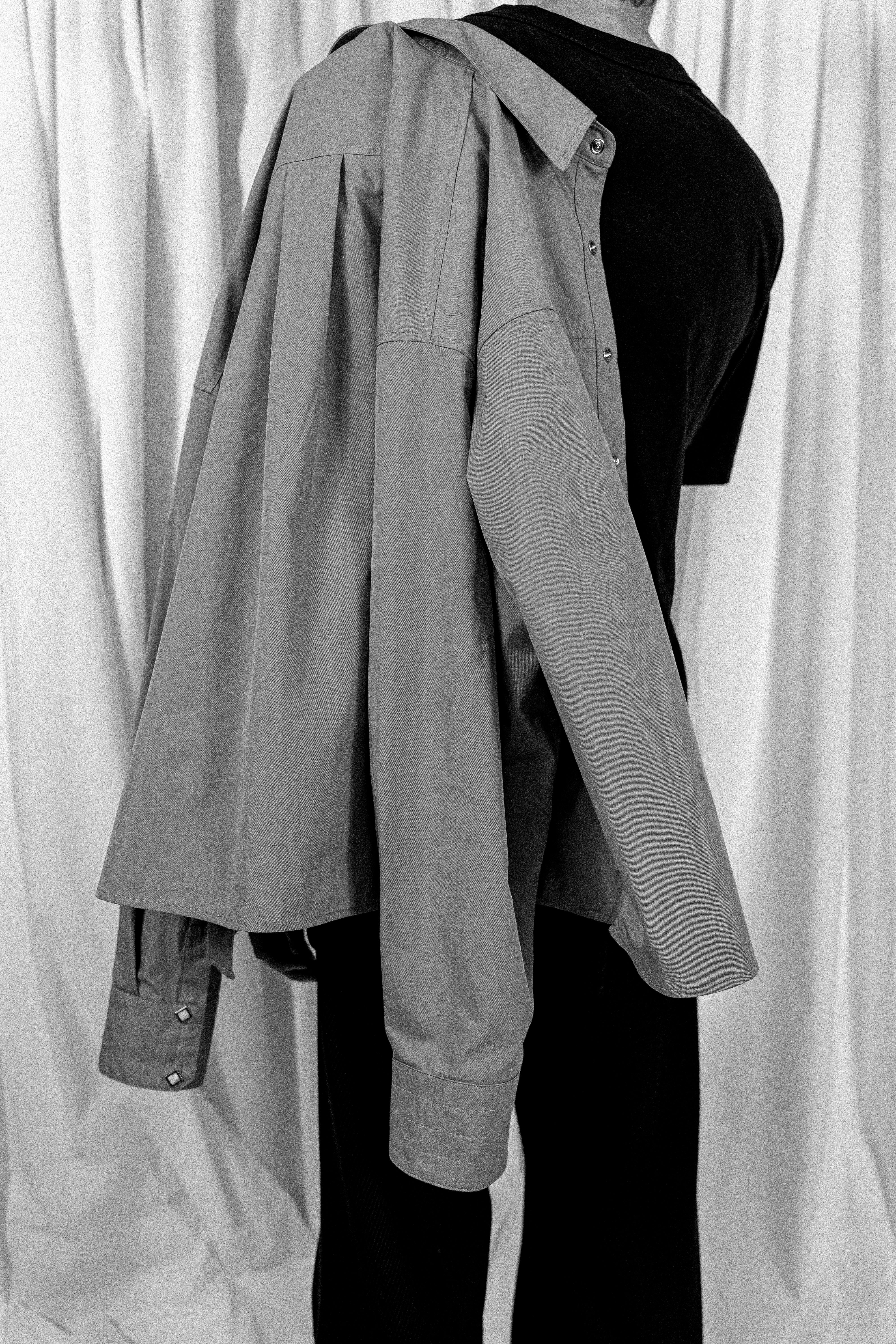 Model hanging cowboy snap button shirt from Misela Studios over his shoulder in aesthetic position