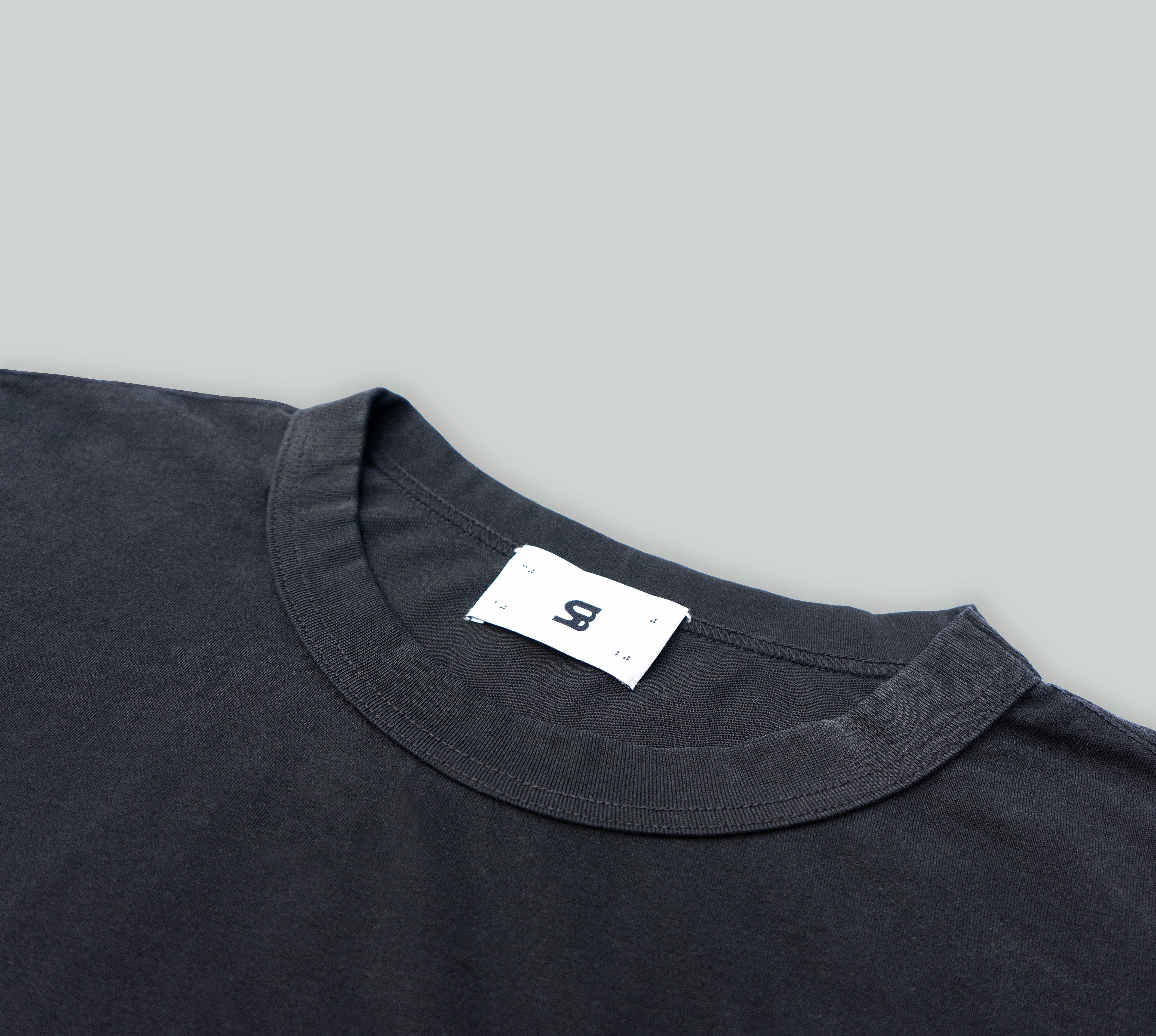 Signature Peral Tee in Black from Misela Studios in front of a cloth screen - Detailview