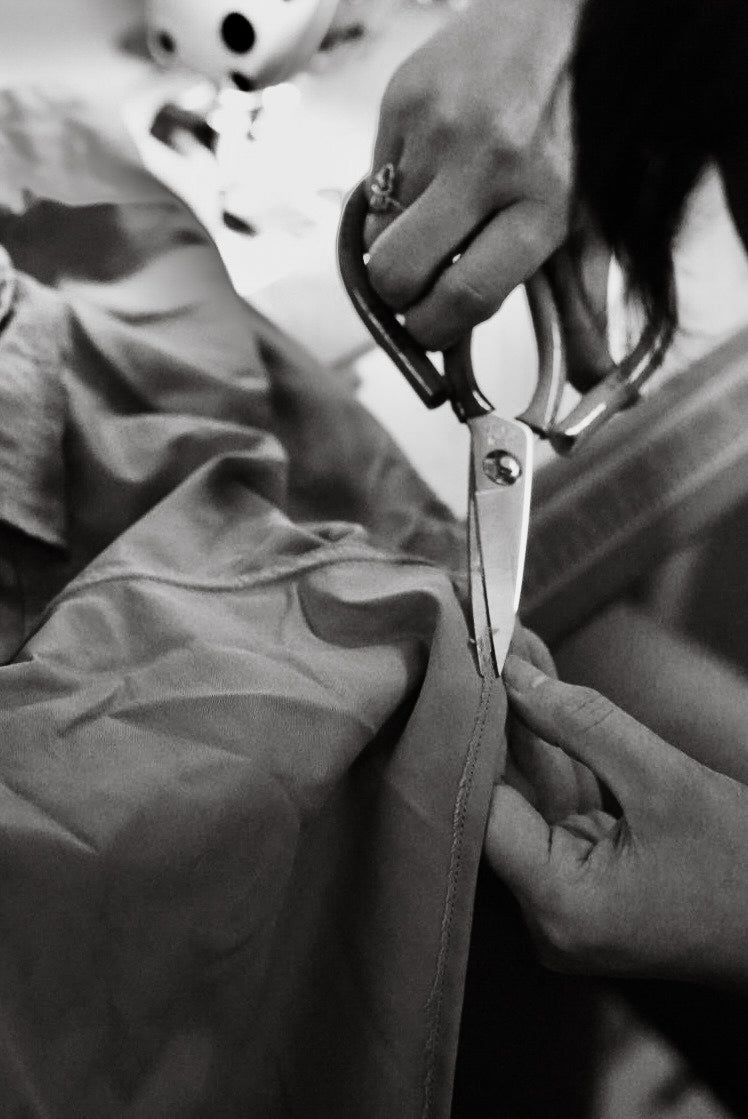 Person cutting with scissor some excess fabric of cowboy snap button shirt from Misela Studios